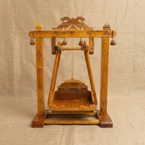 Traditional wooden swing with detailed carved pillars for Thakorji home mandir setup