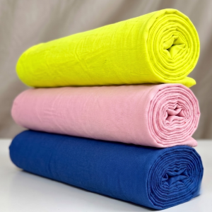 Three rolled plain fabric pieces stacked in a Pushtimargiya shringar combo for Thakorji vastra use