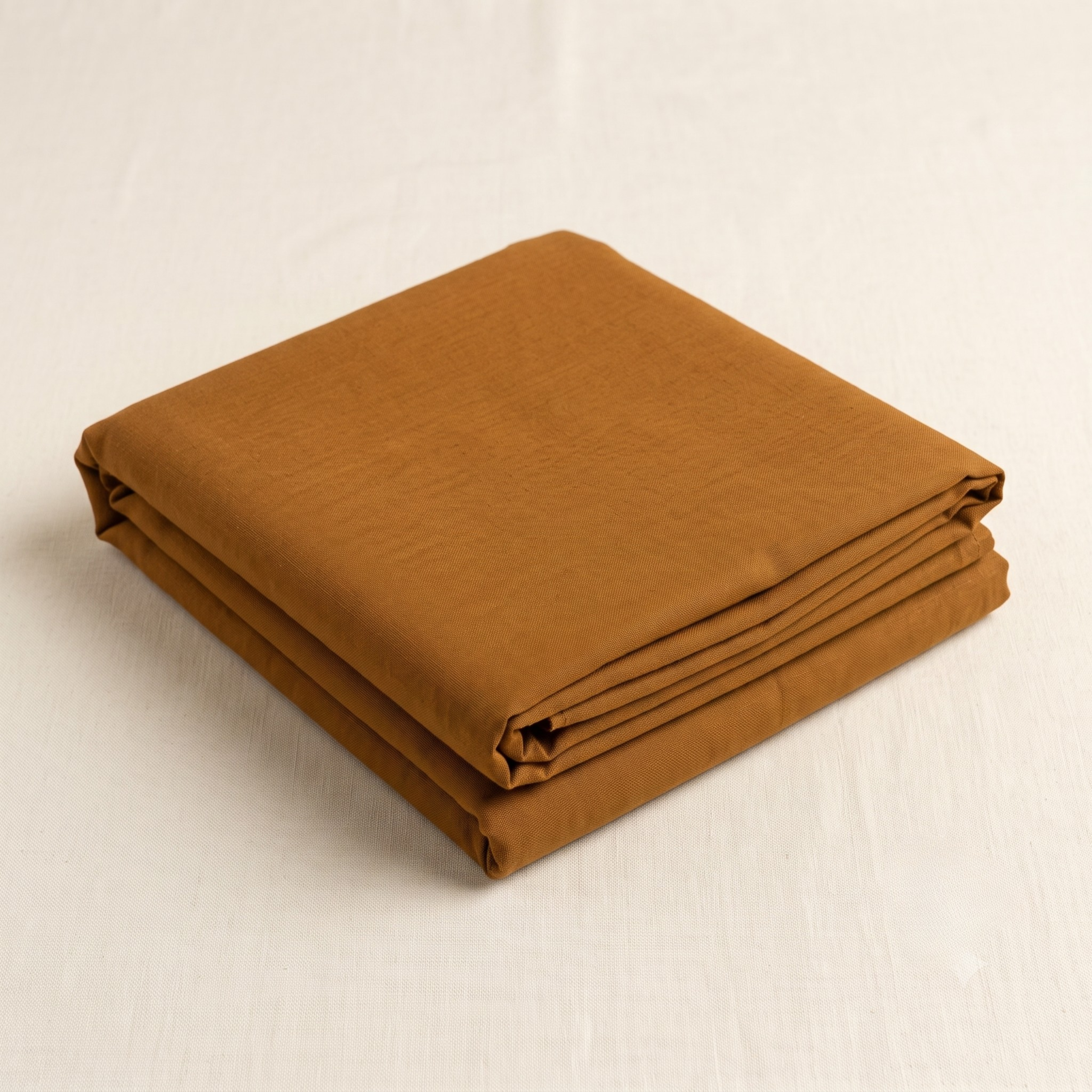 Folded malmal kapda placed neatly on an off-white fabric background.