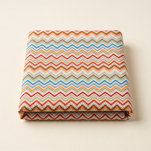 Earth-toned dotted chevron leheriya fabric neatly folded on a light neutral background