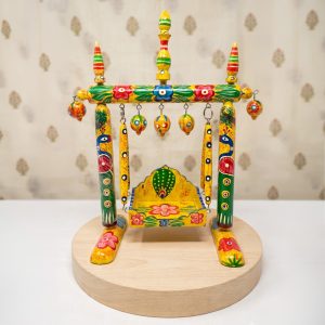Bright yellow hand-painted wooden palna with peacock art for Thakorji Hindola seva setup
