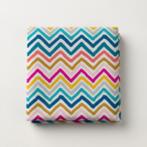 Folded multi-colored chevron leheriya fabric featuring teal, yellow, pink, and grey zig-zag stripes