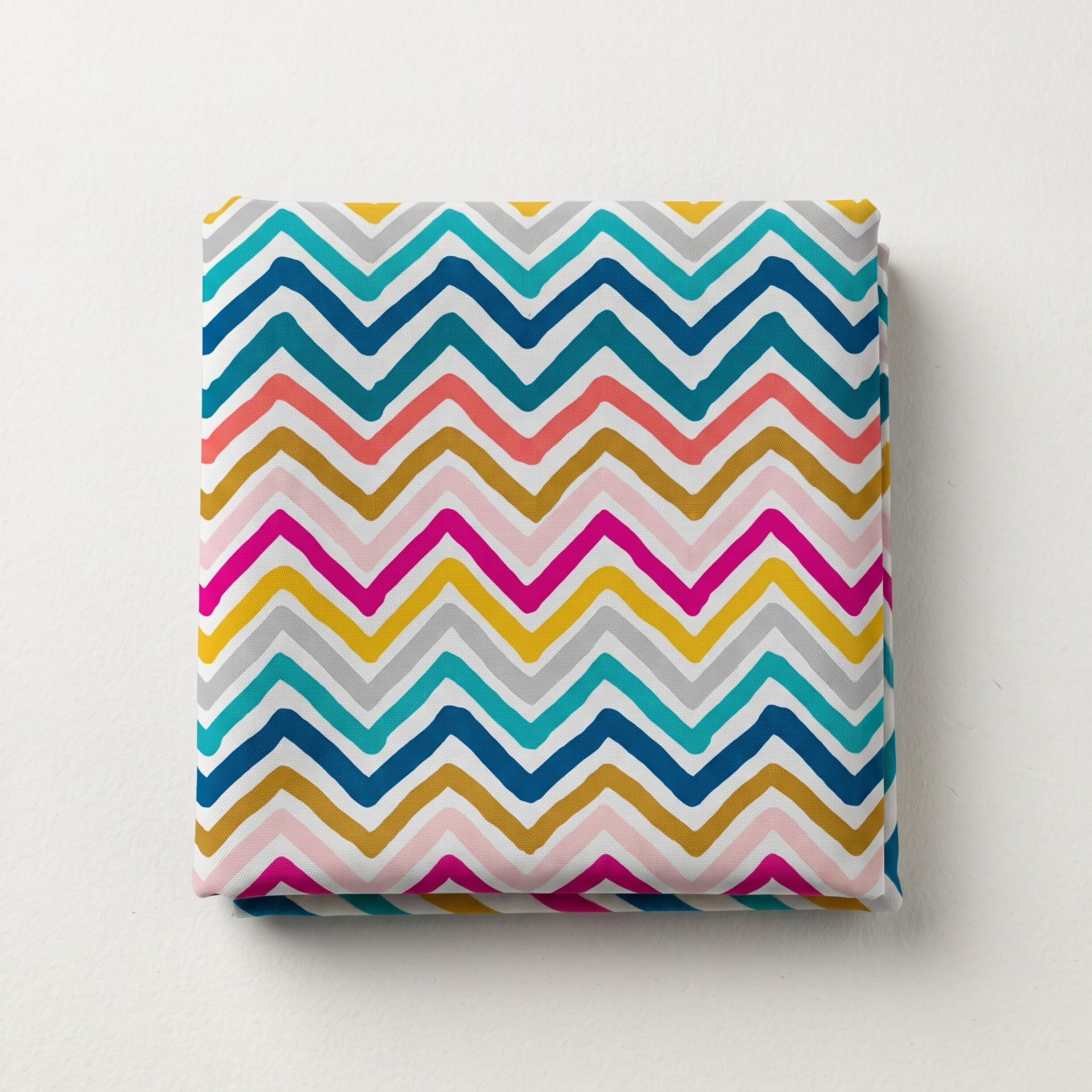 Folded multi-colored chevron leheriya fabric featuring teal, yellow, pink, and grey zig-zag stripes