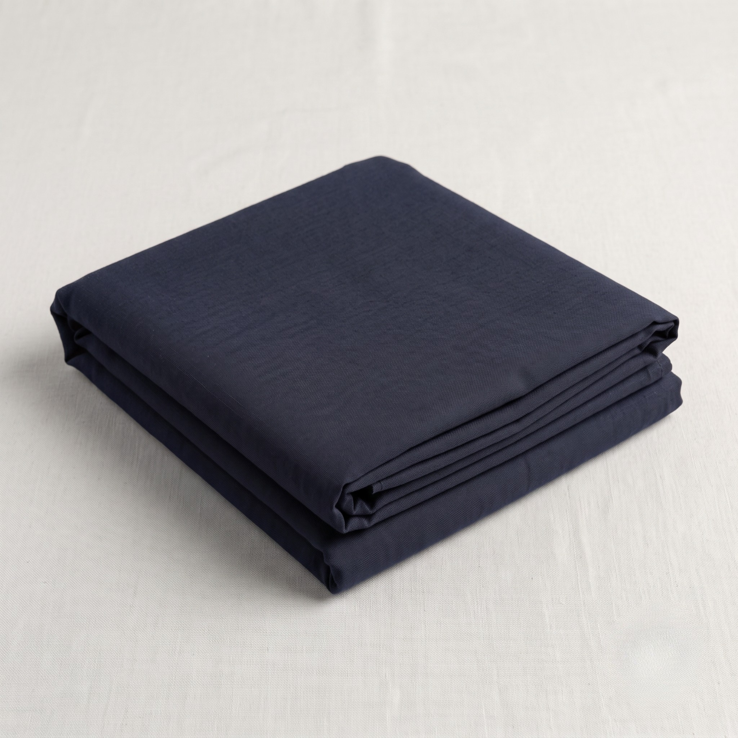 Folded navy blue malmal kapda resting on a textured light beige surface.