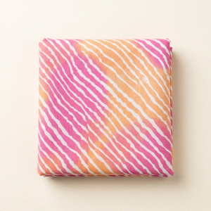 Folded pink and orange dual-tone leheriya fabric with fine white diagonal wave prints