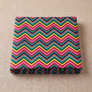 Vibrant rainbow chevron leheriya fabric neatly folded on a textured background